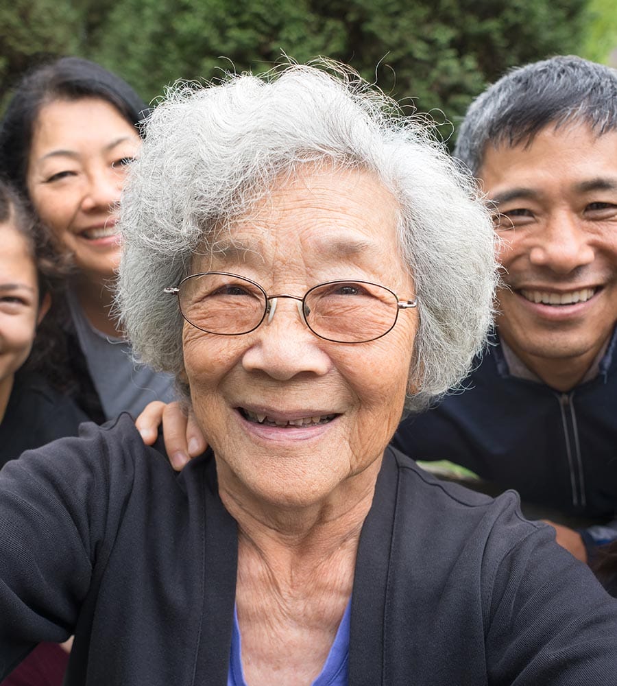 Smiling multigenerational Asian family with an elderly woman in the center, symbolizing the diverse representation of API communities.