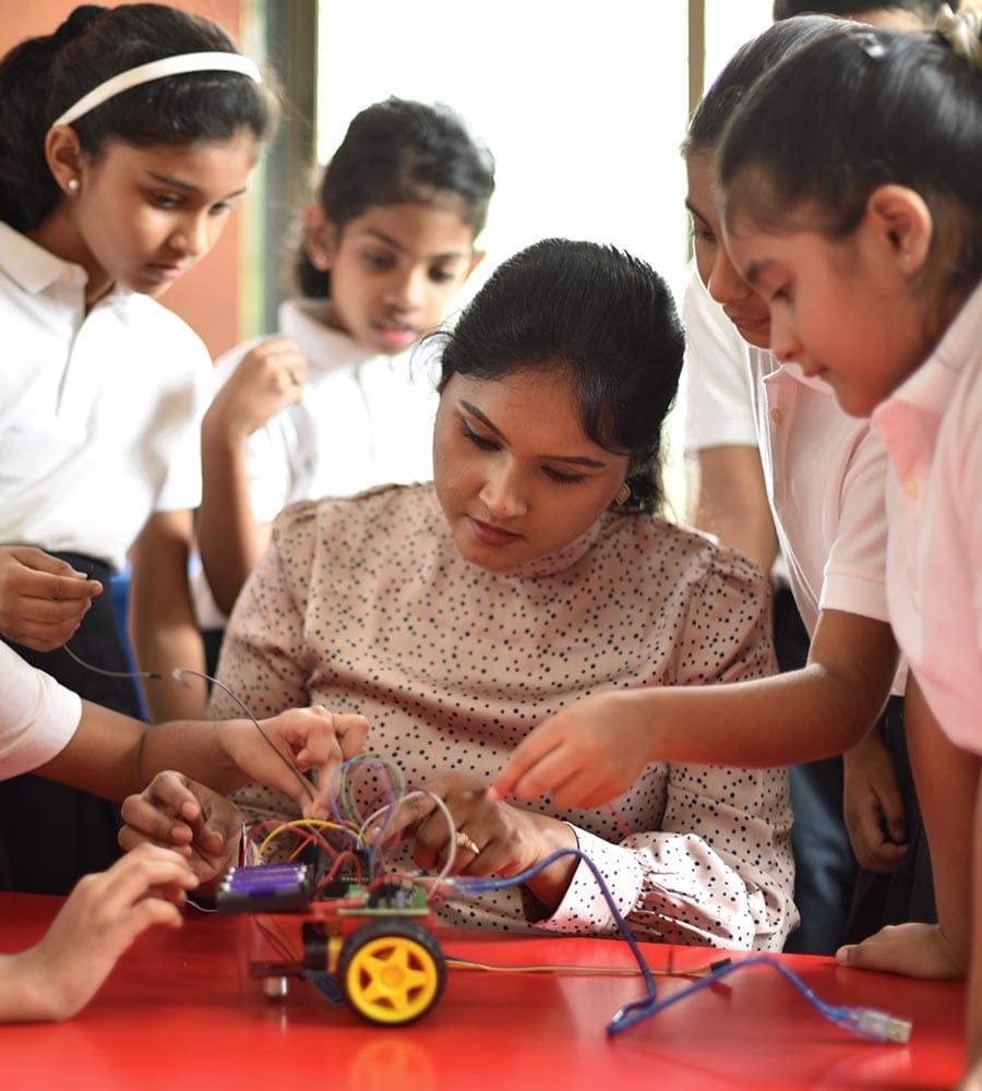 School girls making wiring connections in a robot model car in school