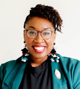 Charlene Polite Corley, Vice President at Nielsen, smiling in a green blazer with statement earrings