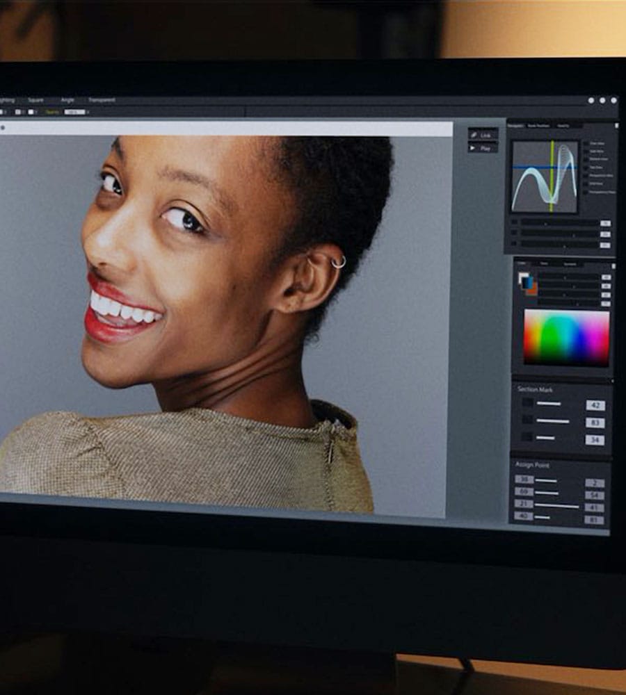 Professional photo editing software displaying a retouched portrait of a smiling woman with short hair on a computer monitor.