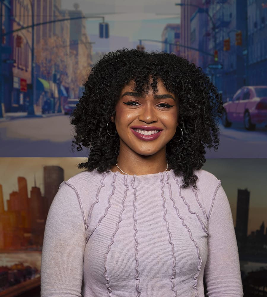 Khaila Amazan, writer of "The Spider Within, is a smiling woman with curly hair wearing a light pink sweater stands against a backdrop of city street and skyline scenes.