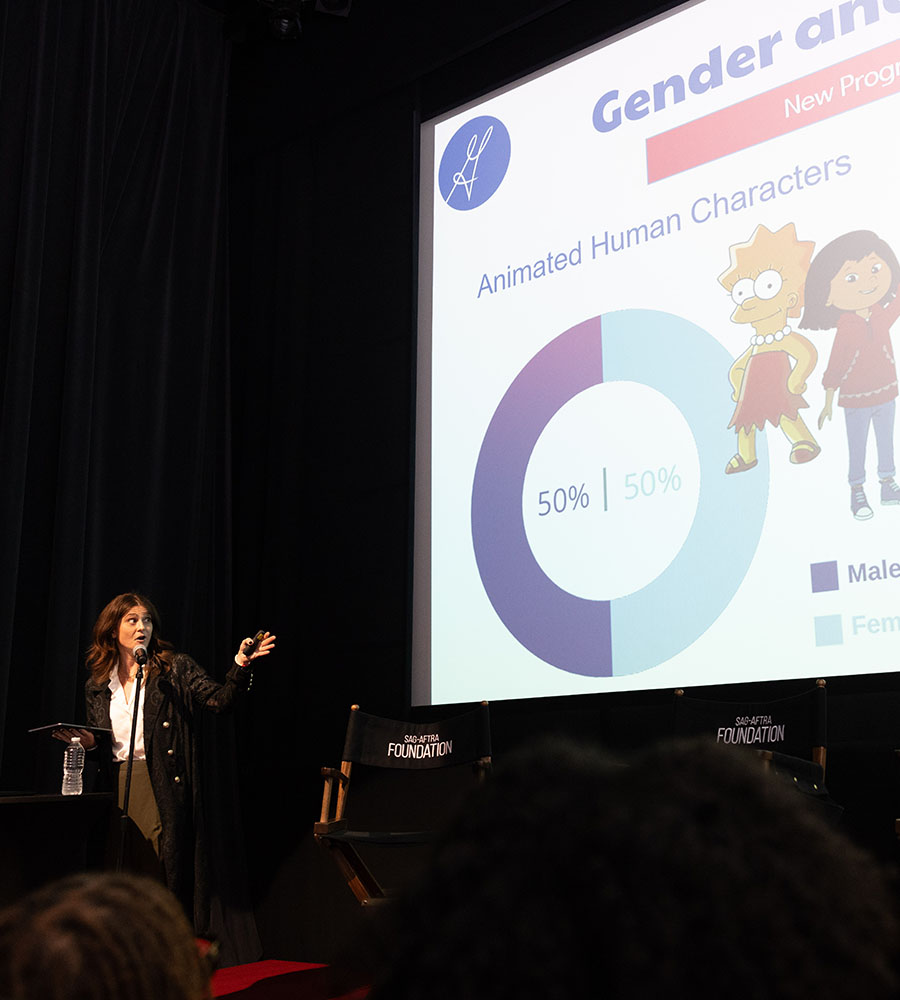 VP of Research and Insights stands on stage in front of a large screen displaying a slide with the title 