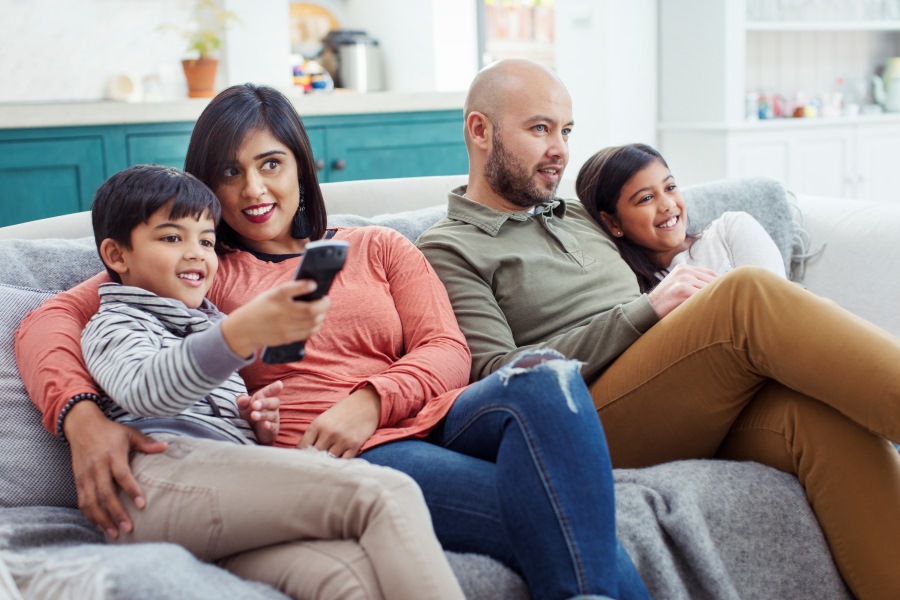 Family watching TV on living room sofa