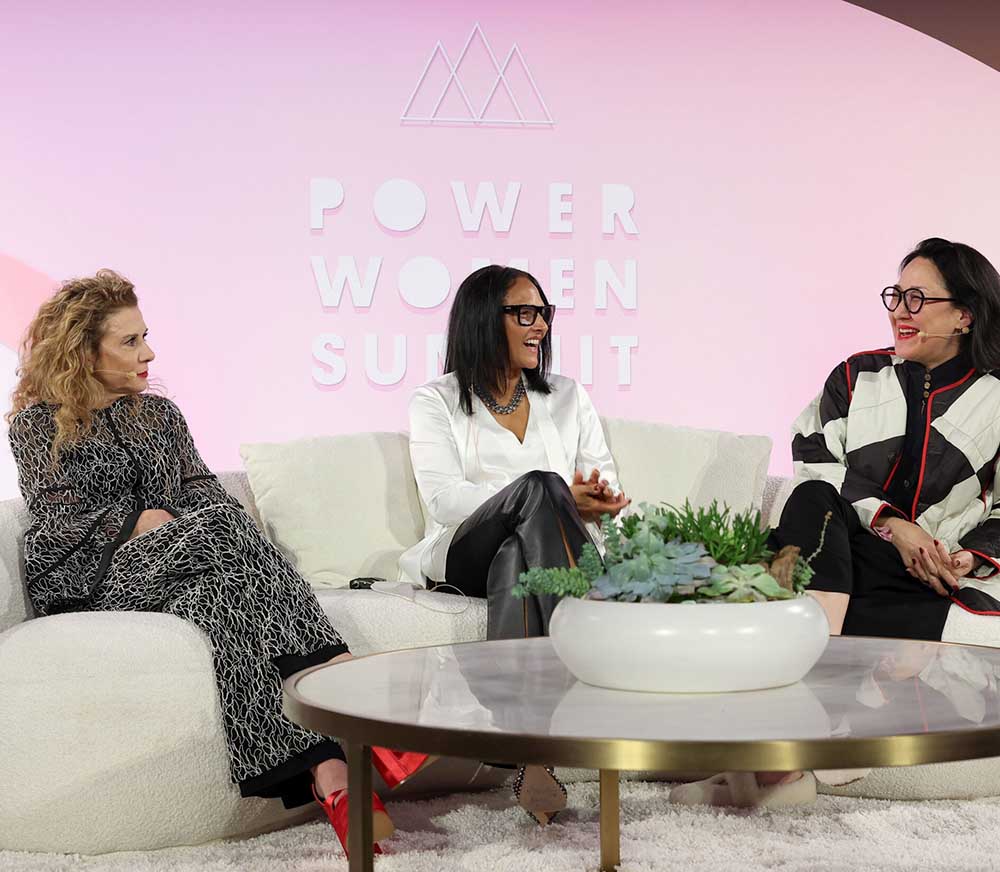 Madeline Di Nonno, Janine Jones-Clark, and Ramsey Naito seated onstage at the Power Women Summit, discussing film representation. The stage has a pink 