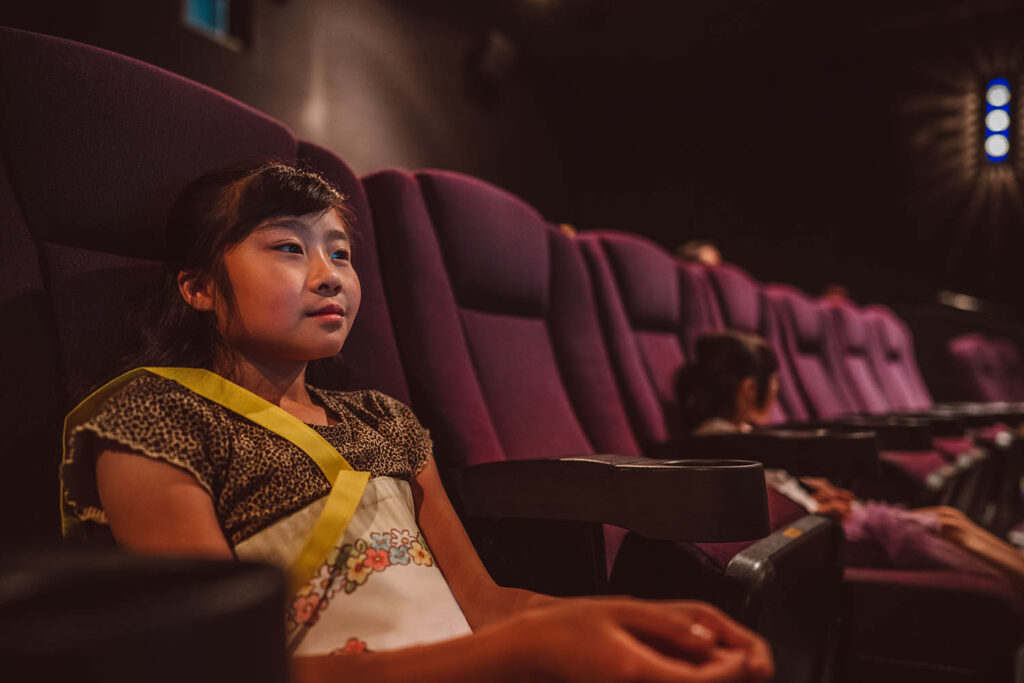 Lovely girl watching movie in cinema hall at movie theatre