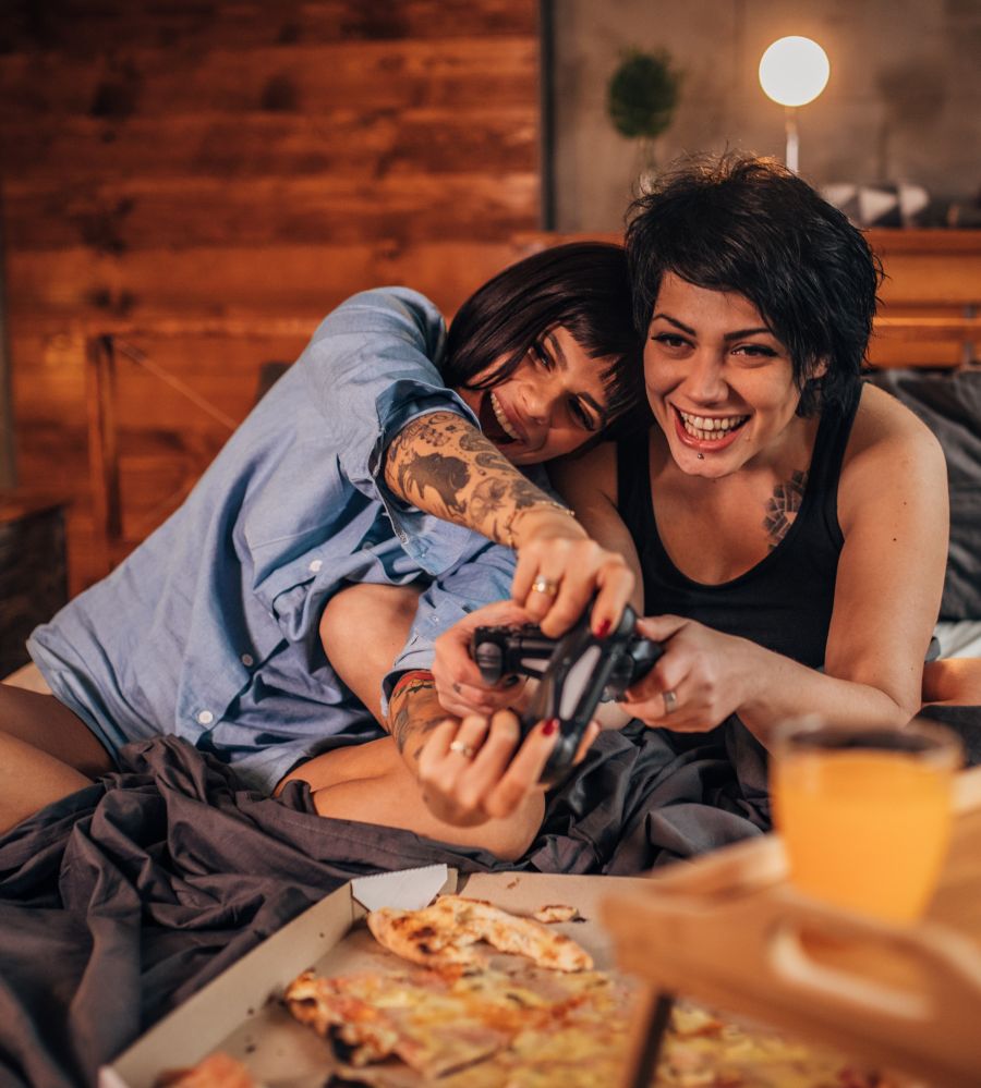 Young white lesbian couple plays video games at home smiling