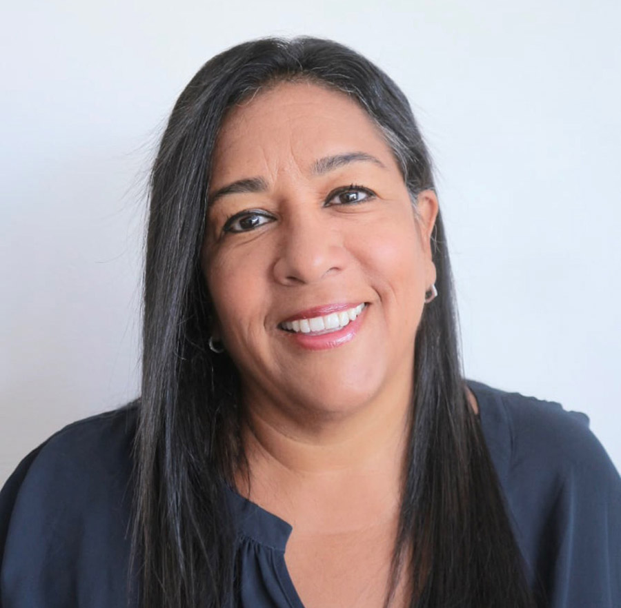 Marcela Escobar-Alava smiling in a professional headshot, wearing a dark blouse with straight, dark hair against a light background