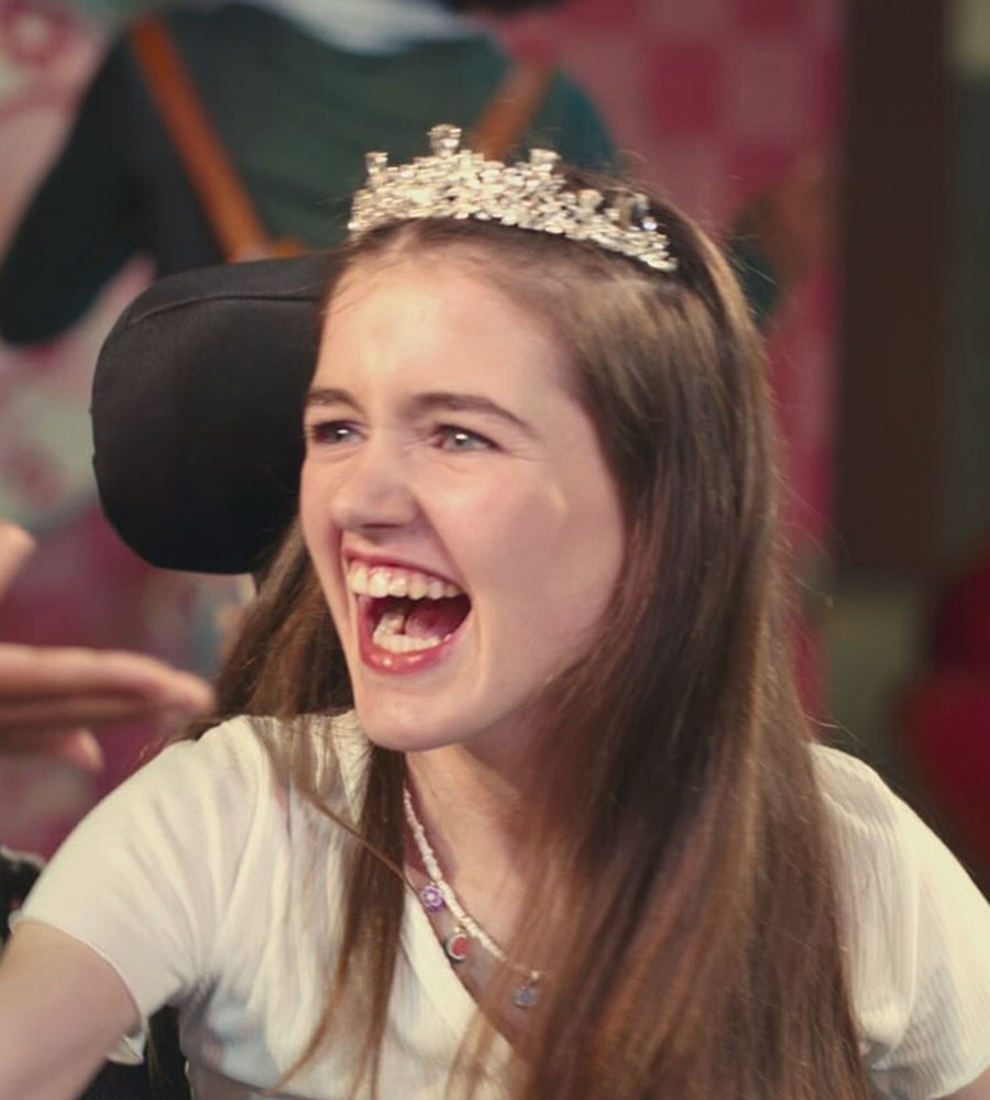 Phoebe-Rae Taylor smiling with arms raised in a wheelchair as Melody Brooks in Disney's Out of My Mind