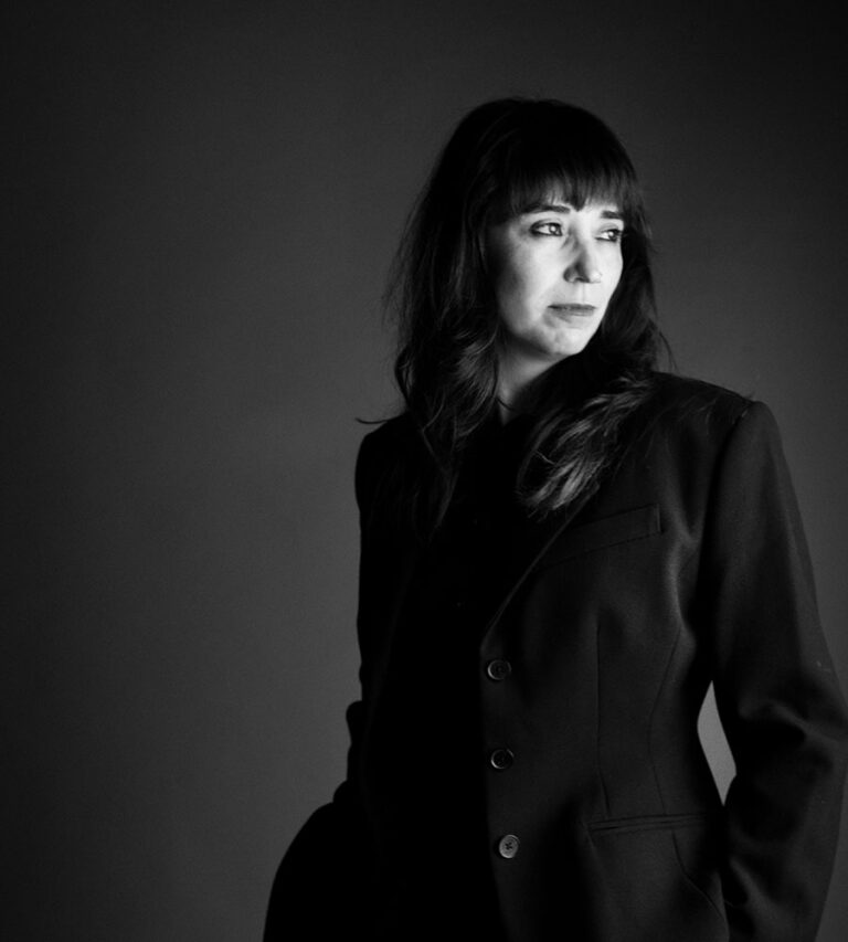 Black-and-white portrait of director Michelle Garza Cervera wearing a dark blazer and looking thoughtfully off to the side.